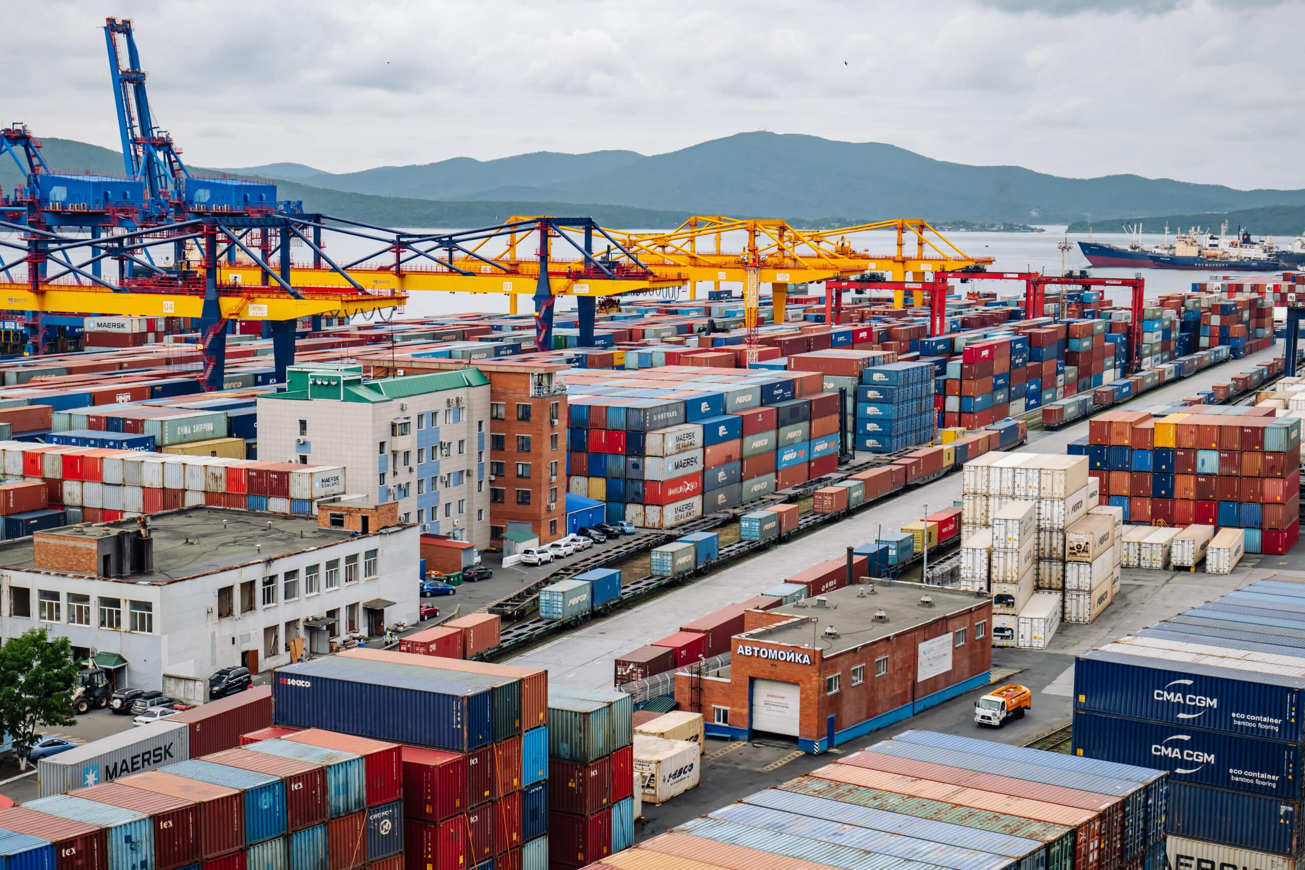 Cargo cranes loading and unloading vibrant shipping containers at a bustling commercial port terminal in russia, highlighting global logistics